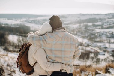 Baba çocuğunu kucaklıyor, karlı bir manzaraya bakıyor. Açık hava macerasında aile bağını, sevgiyi ve birlikteliği kutluyoruz.