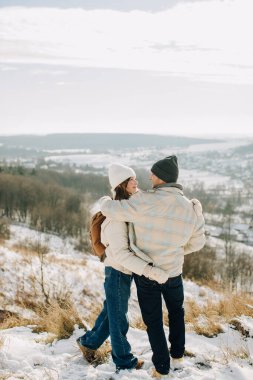 Baba ve kızı karlı bir yamaçta kucaklaşıyorlar, açık hava kış macerası sırasında hassas bir anı paylaşıyorlar.