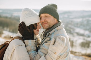 Baba ve kızı, güneşli bir kış gezisinde sıcak bir kucaklaşmayı ve açık havada hassas bir anı paylaşıyor, aile sevgisini sergiliyor.