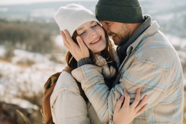 Sevgi dolu baba, gülen kızını sıcak kış kıyafetleriyle kucaklıyor, dışarıda aile bağlarının tadını çıkarıyor.