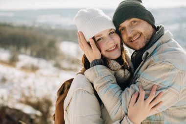 Baba ve kız kucaklaşıyorlar, kameraya gülümsüyorlar. Sevgi dolu aile, kış manzarasında birlikte vakit geçiriyor. Bağlanma ve mutluluk