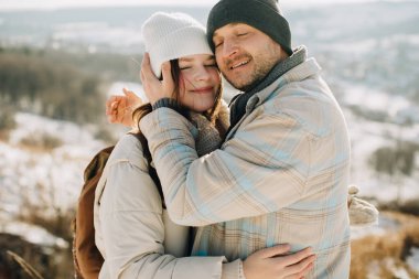 Baba, karlı bir kış gezisinde kızını sevgi ve sevgiyle kucaklıyor. Güçlü bir aile bağı gösteriyor.