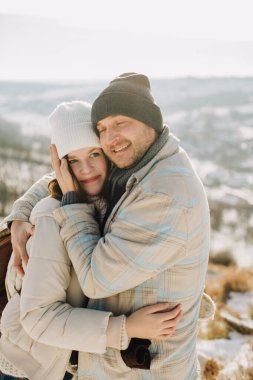 Mutlu bir baba, küçük kızını karlı bir dağda kucaklıyor. Kışın sevgi dolu, sıcak bir aile anını paylaşıyor.