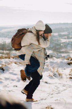 Baba kızını sırtında taşıyor, karlı bir arazide eğlenceli bir kış gezintisi yapıyor. Babalık bağı ve aile aktivitesi