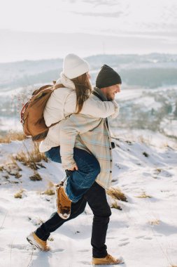 Babası kızını sırtında taşıyor. Kışın açık hava aktivitelerinde aile bağlarını ve neşeli anları gösteriyor.