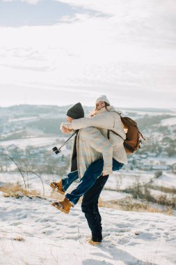 Baba, kızını karlı tepede sırtında taşıyor. Kışın aile gezisi, kaynaşma ve macera.