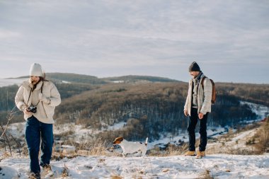 Dad and daughter walking with their loyal jack russell dog on a snowy mountain trail during winter enjoying nature