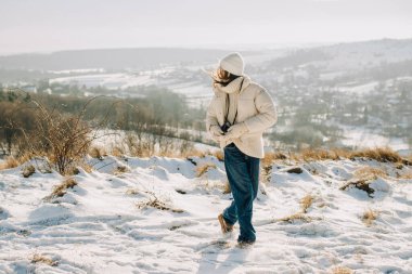 Sıcak giysiler içinde karlı dağ manzaralarını keşfeden kadın soğuk havanın ve açık havanın tadını çıkarıyor.