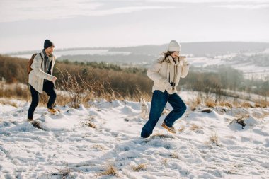 Baba ve kızı kış gezintisinin keyfini çıkarıyorlar, küçük köpekle karlı doğada koşuyorlar, mutluluğu ve aile bağlarını paylaşıyorlar.