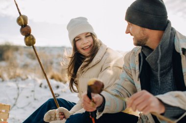 Baba ve kızı birlikte vakit geçiriyorlar, gülüyorlar ve aile pikniğinde elma kızartıyorlar.