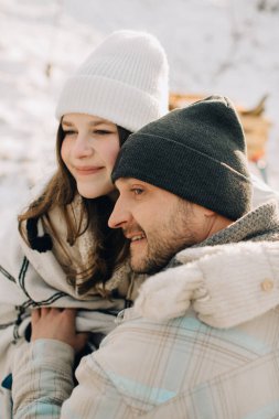 Gülümseyen baba ve kızı karlı bir kış manzarasında sıcaklığı ve neşeyi buluyorlar, sevgi dolu bir kucaklaşmayı paylaşıyorlar.