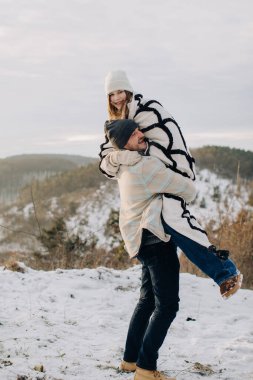 Baba, neşeli kızını sırtında taşıyor, karlı bir arazide kış gezisinde birlikte eğleniyor.