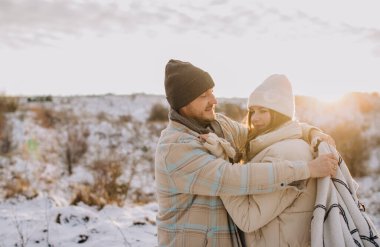 Baba ve kızı, karlı bir kış öğleden sonrasında sıcak bir kucaklaşmayı paylaşıyor. Barışçıl doğa manzarasının ortasında paltoları ve taksilerle sarmalanmış.