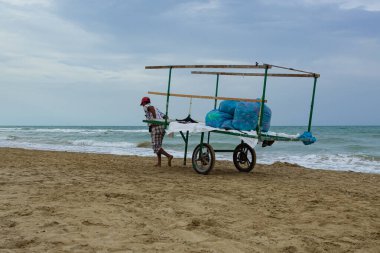 Büyük kargolarla dolu bir araba deniz kenarındaki kumlu sahilde dalgalarla ve bulutlu gökyüzüyle bekliyor. Ulaşım, iş ve kıyı yaşam tarzı kavramı.