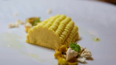 Zarif tabakta gurme tatlısı, karamel parçacıkları, katmanlı hamur işleri ve dekoratif öğeler içeren sanatsal bir sunum. mısırın başı