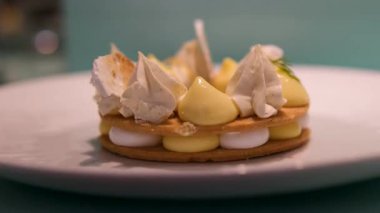 Sarı ve beyaz kremalı krema içeren ince katmanlı tatlı. Beyaz bir tabakta güzel bir şekilde düzenlenmiş. Güzel bir yemek sunumu..