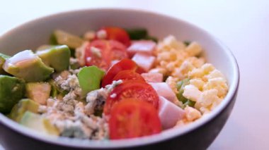 Yavaş çekimde tavukları beyaz kasede taze salataya koyan Sezar Salatası hazırlığı. Yüksek kalite 4k görüntü