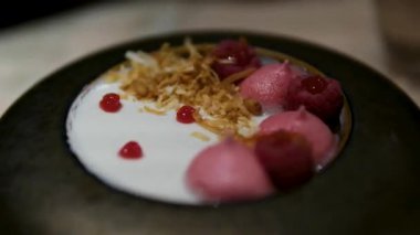 Kremayla süslenmiş böğürtlenli panakota tatlısına ve siyah ayna arka planında cam kaplarda otlara odaklan. Yüksek kalite 4k görüntü