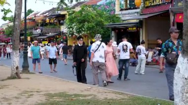 Otantik Hoi Bir Vietnam yaşam tarzı turistlerin canlı kültürel seyahat sahnelerinde yürüdüğü eski şehir caddeleri nehirde yüzen tekneler ve kafede eğlenen insanlar. Hoi Bir Vietnam 10.02.2025