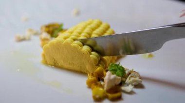 Gerçekçi mısır şekilli ezme beyaz bir tabakta özgün moleküler gastronomi yemek sunumunda kremsi doku sanatsal ve yenilikçi mutfak tasarımı ile servis edilir..