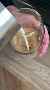 Kahve barmeninin sütünü bir fincana doldurması latte sanatı, yakın çekim kahve yapma süreci yaratıyor. latte yapma süreci