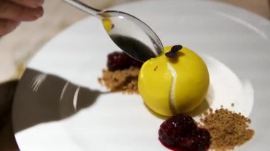 Sarı soslu, beyaz peynir ve ahşap masaya konmuş mor çiçeklerle süslenmiş bir tatlı tabağı manzarası. Yüksek kalite 4k görüntü