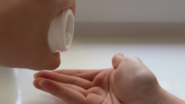 Kadın elleri, küçük bir şişeden beyaz tabletleri beyaz bir pencere eşiğine dökerek günlük sağlık rutinini ve dikkatli sağlık uygulamasını kullanır..