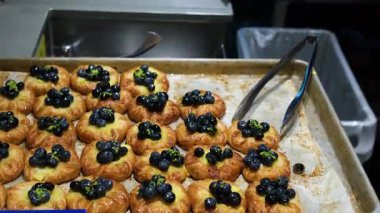 Kremalı ve böğürtlenli hamur işleri, iştah açıcı bir gösteri için güzel bir tepside dizilmiş. Lokina üzümü.