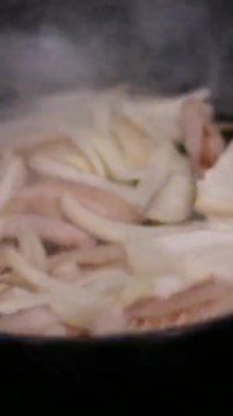 Kızarmış et. Aşçı, et parçalarını soğanla karıştırıp gaz sobasında kızartma tavasına koyar. Yüksek kalite 4k görüntü