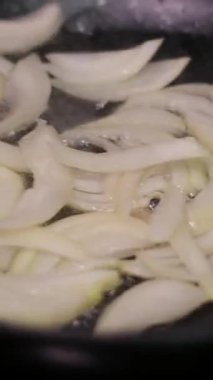 Doğranmış soğanlar sebze yağında tavada kızartılır, ara sıra karıştırılır. Yakın plan. Yüksek kalite 4k görüntü