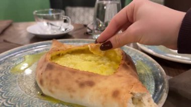 Geleneksel Gürcistan khachapuri peynirli ekmeğine yakın plan, yumurtaların üstünde otantik Doğu Avrupa mutfağı, yemek kültürü ve ev yapımı tatlar sergileniyor. Yüksek kalite 4k görüntü