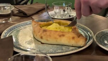 Geleneksel Gürcistan khachapuri peynirli ekmeğine yakın plan, yumurtaların üstünde otantik Doğu Avrupa mutfağı, yemek kültürü ve ev yapımı tatlar sergileniyor. Yüksek kalite 4k görüntü