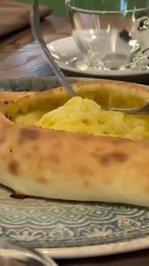 Geleneksel Gürcistan khachapuri peynirli ekmeğine yakın plan, yumurtaların üstünde otantik Doğu Avrupa mutfağı, yemek kültürü ve ev yapımı tatlar sergileniyor. Yüksek kalite 4k görüntü