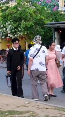 Otantik Hoi Bir Vietnam yaşam tarzı turistlerin canlı kültürel seyahat sahnelerinde yürüdüğü eski şehir caddeleri nehirde yüzen tekneler ve kafede eğlenen insanlar. Hoi Bir Vietnam 10.02.2025