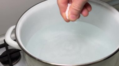 Mutfakta Şef Tuzlu Yemekler. Tencerede Kaynar Su. Şef tabağa tuz ekliyor. Yemek ateşte kaynıyor. Mutfakta Mutfak Mutfağı. Şef Yemekleri Hazırlıyor. Makarna pişirmek için tencerede tuzlu su..