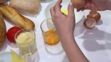 Tavuk yumurtalarını beyaz ve yumurta sarılarına ayırmak, parlak bir ev mutfağında, elleri kahverengi yumurtayı ahşap masadaki beyaz kaselerin üzerinde dikkatlice tutmak, pişirme, pişirme, ev yapımı.