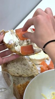 Şef tostun üstüne krem peynir sürer, sağlıklı bir kahvaltı veya atıştırmalık hazırlar. Dilimlenmiş avokado ve tütsülenmiş somon yakında bekliyor. Yüksek kalite 4k görüntü