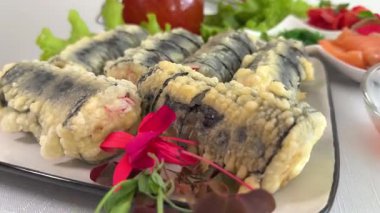 Sushi dürümleri pirinç, yosun, karides, salatalık ve balık yumurtası Japon mutfağının çekici bir sunumunu oluşturuyor. Japon suşisi ve makaralı makro görüntüler. Yüksek kalite 4k