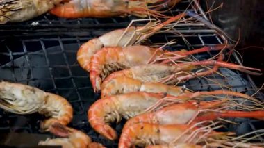 Chef cooking shrimps with oil and spices on grill close-up. Prawns on fire throwing them on pan. Dorado and salmon fish steak on frying grill. Restaurant Food concept. Sea food.