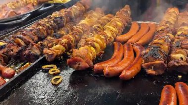 Gaz barbeküsünde ızgara et şişleri, sosisler ve mısır. Dışarıda yemek pişirirken ızgaradan duman yükselir. Piknik ya da arka bahçe partisi için lezzetli yaz yemeği hazırlığı. Yüksek kalite 4k