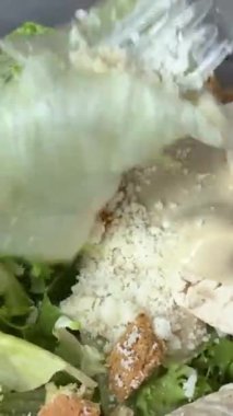 Sezar salatasını trendeki tüm malzemelerle birlikte plastik bir kabın içinde hazırlıyorum. Yüksek kalite 4k görüntü