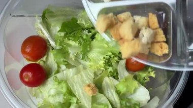 Sezar salatasını trendeki tüm malzemelerle birlikte plastik bir kabın içinde hazırlıyorum. Yüksek kalite 4k görüntü