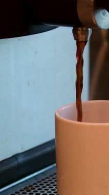 Dipsiz filtresi olan profesyonel bir kahve makinesinden Espresso kahve özütü yakın plan. Kahve fincana akıyor. Kahve aroması ve sıcak dükkan atmosferi. Yüksek kalite 4k görüntü