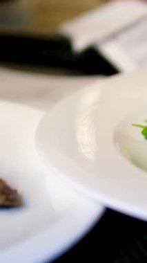 Ispanaklı lezzetli kuzu şiş porsiyonları açık büfe masasında her beyaz tabak için üç tane sunuluyor. Şık gurme yemek sunumu restoran ya da etkinlik yemeği için mükemmel..