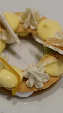 Sarı ve beyaz kremalı krema içeren ince katmanlı tatlı. Beyaz bir tabakta güzel bir şekilde düzenlenmiş. Güzel bir yemek sunumu..