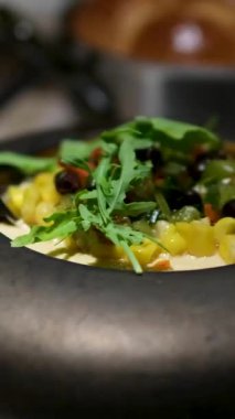 Loş aydınlatılmış bir restoranda sade ve zarif bir yemek atmosferi yaratan sade bir çömlekte servis edilen roka mısır ve yumurta sağlıklı organik gıda aşıkları için mükemmel..