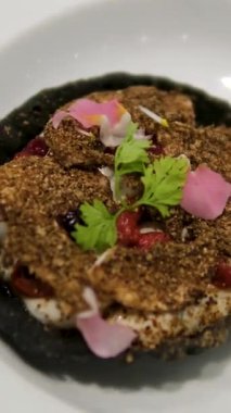 Ezilmiş fındık ve taze kişniş yaprağıyla süslenmiş kremalı salata karışımıyla dolu şık, siyah, yenilebilir sepet. Beyaz tabak üzerine zarif bir kaplama..