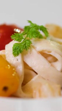 Geniş erişteler, yarı yarıya kiraz domatesleri ve ince yemek sunumunda doku ve renkleri gösteren ipek kremalı soslu sanatsal tabakların yer aldığı gurme makarna tabağının yakın çekimi..