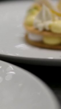 Sarı soslu, beyaz peynir ve ahşap masaya konmuş mor çiçeklerle süslenmiş bir tatlı tabağı manzarası. Yüksek kalite 4k görüntü