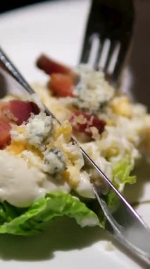 Marul, tavuk ve peynir dahil çeşitli malzemelerle dolu bir kase salata. Salata mavi bir tabakta servis edilir ve o sağlıklı ve iştah açıcı bir yemektir. Yüksek kalite 4k görüntü